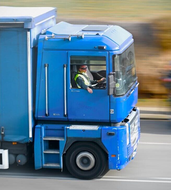 Dynamic panning shot capturing a blue truck in motion on a highway in daylight.